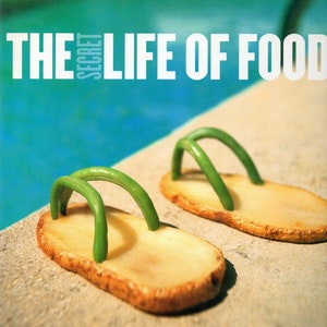 May include: A creative food art image featuring two potato slice sandals with green bean straps. The sandals are placed on a stone surface with a turquoise blue water background. The text "THE SECRET LIFE OF FOOD" is at the top.
