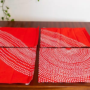 May include: Four red placemats with a white polka dot pattern. The pattern is a series of concentric circles.