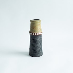Könnte beinhalten: Eine kleine, keramische Vase mit einer strukturierten, schwarzen und grünen Glasur. Die Vase hat ein braunes Band mit weißen Punkten um die Mitte.