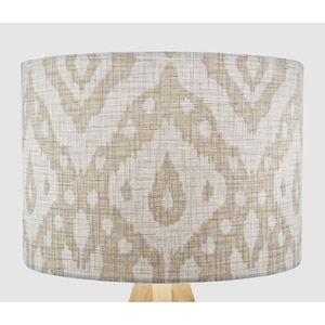 May include: A beige lampshade with a white and brown geometric pattern. The lampshade is made of fabric and has a cylindrical shape.