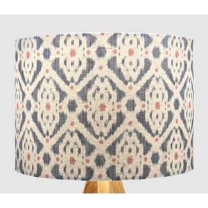May include: A white lampshade with a blue and pink ikat pattern. The lampshade is cylindrical and has a fabric texture.