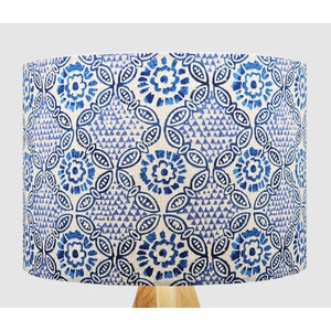 May include: A white lampshade with a blue and white floral pattern. The lampshade is cylindrical and has a white background with blue flowers and leaves.