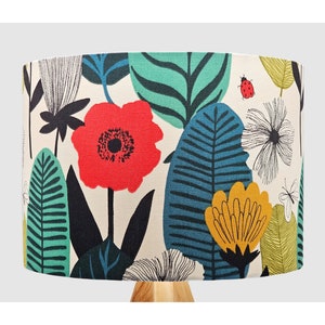 May include: A lampshade with a floral print featuring red, yellow, and blue flowers, green leaves, and a ladybird on a white background.