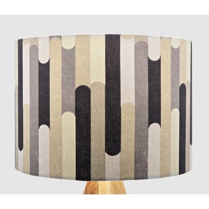 May include: A lampshade with a geometric pattern in shades of beige, grey, and black. The pattern features vertical stripes and curved shapes.