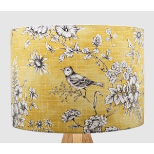 May include: A yellow lampshade with a black and white floral pattern featuring a bird. The lampshade has a linen texture.