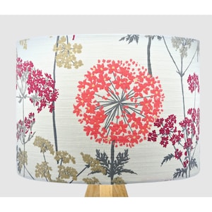 May include: A white lampshade with a floral pattern featuring red and pink flowers on a grey background.