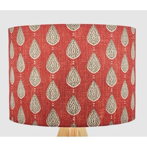 May include: A red lampshade with a white and grey teardrop pattern. The lampshade is made of fabric and has a textured surface.