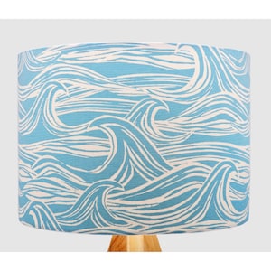 May include: A blue and white lampshade with a wave pattern. The waves are white on a light blue background.