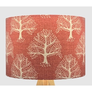 May include: A red lampshade with a white tree pattern. The lampshade is made of fabric and has a textured surface.