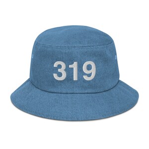 Pode incluir: Um chapéu de balde de brim azul com o número 319 bordado em branco na frente.