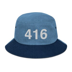 May include: A blue denim bucket hat with a contrasting dark blue brim. The hat has the number "416" embroidered in white on the front.