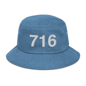 Pode incluir: Um chapéu de balde de brim azul com o número "716" bordado em branco na frente.
