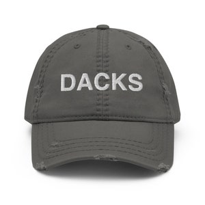 May include: A gray distressed baseball cap with the word "DACKS" embroidered in white on the front.