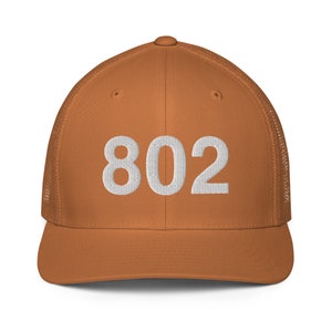 May include: A brown and white trucker hat with the number 802 embroidered on the front.