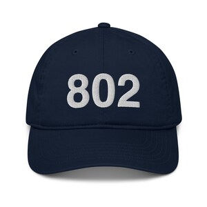 May include: A navy blue baseball cap with white embroidered text that reads "802".