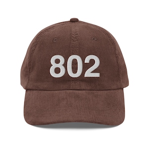 May include: A brown corduroy baseball cap with the number 802 embroidered in white on the front.
