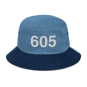 May include: A blue denim bucket hat with a contrasting dark blue brim. The hat has the number "605" embroidered in white on the front.