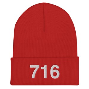 May include: Red knit beanie with a white embroidered number "716" on the front.