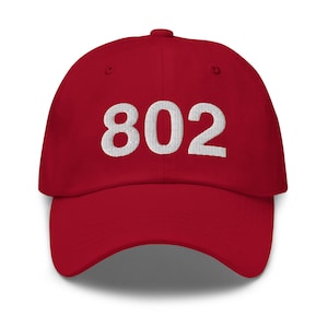 May include: A red baseball cap with white embroidered text that reads "802".