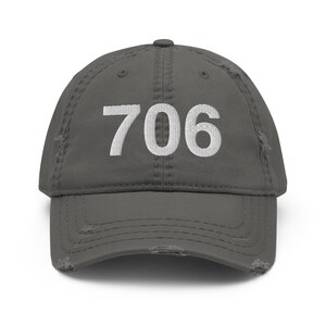 May include: A grey distressed baseball cap with the number 706 embroidered in white on the front.