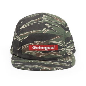 May include: A camouflage 5-panel cap with a red patch that says "Gabagool" in white lettering.