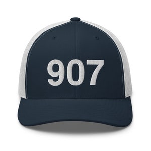 May include: A navy blue and white trucker hat with the number 907 embroidered in white on the front.