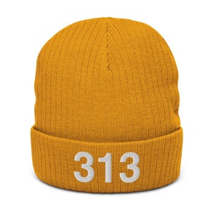 Puede incluir: Un gorro de punto amarillo mostaza con el número "313" bordado en blanco en la parte delantera.