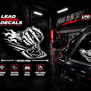 May include: A white vinyl decal featuring a skeletal hand gripping a manual gear shifter with flames trailing behind. The design includes the text LEAD PEDAL DECALS MADE TO BE SEEN and LPD ORIGINAL. A measurement line indicates the decal is 7 inches wide.