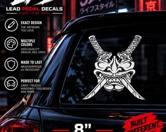 May include: A white vinyl decal featuring a stylized samurai mask with two crossed katanas, applied to a car window. The decal measures 8 inches. Text on the image includes LPD LEAD PEDAL DECALS, JDM, and BUILT DIFFERENT, along with product feature icons.