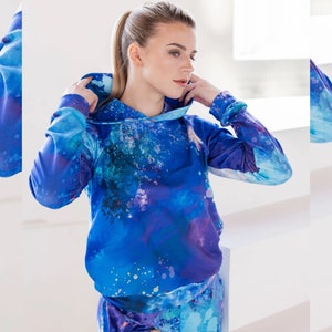 May include: A blue hoodie with a colorful abstract print. The hoodie has a drawstring hood and long sleeves.