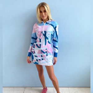 May include: A blue and pink hooded dress with an abstract print. The dress has a zipper closure and long sleeves.