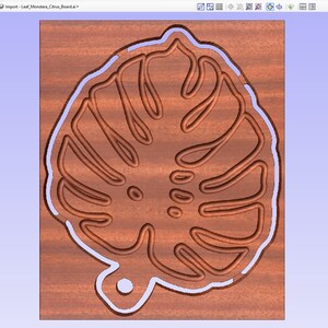 May include: A close-up of a wooden leaf pattern with a light brown color. The leaf is outlined in a light blue color and has a small hole at the bottom.