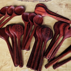 Puede incluir: Una colecci&oacute;n de cucharas de madera, esp&aacute;tulas y utensilios de servicio de color caoba rojo oscuro. Cada utensilio tiene un dise&ntilde;o &uacute;nico y est&aacute; grabado con un mensaje personalizado.