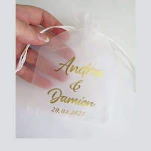 May include: White organza bag with gold lettering that reads "Andrea & Damien 20.04.2024".