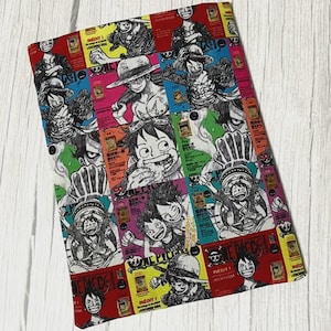 May include: A rectangular fabric item with a vibrant manga-style collage. The design features multiple panels with character illustrations and text, set against a backdrop of red, yellow, green, and pink.