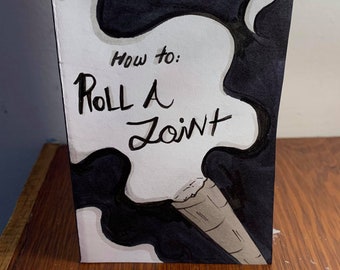 May include: A white booklet with black ink illustrations of smoke and a rolled joint. The title of the booklet is "How to: Roll a Joint" and the author is "Julia Brake".