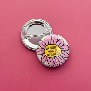 May include: A pink and yellow flower button with the text "You belong among the wildflowers".