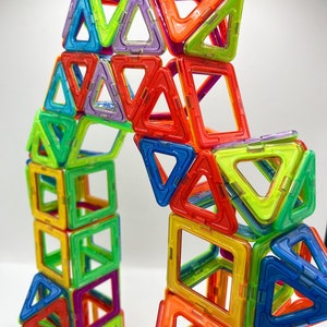 Op de afbeelding: Een kleurrijke magnetische bouwset met verschillende vormen, waaronder driehoeken en vierkanten. De set is gemaakt van felgekleurd plastic en is ontworpen voor kinderen om structuren te bouwen.