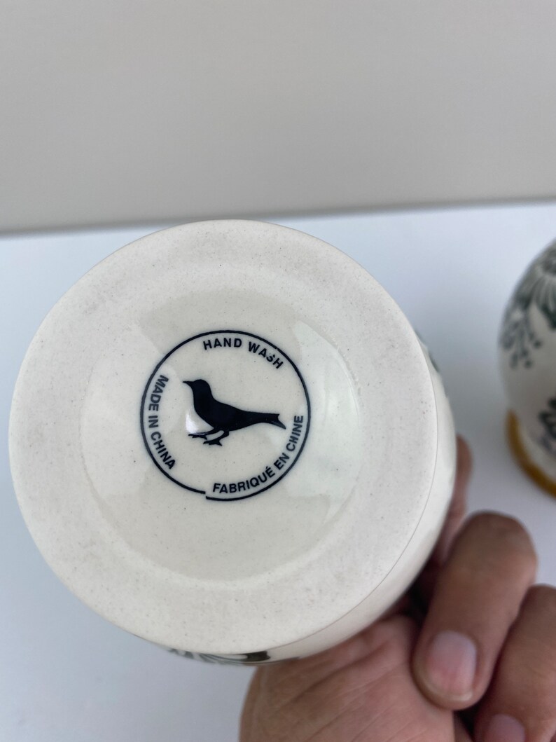 Może przedstawiać: Biały ceramiczny wazon z czarnym wzorem ptaka i tekstem "HAND WASH MADE IN CHINA FABRIQUE EN CHINE" na spodzie.