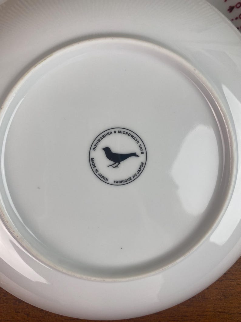 May include: White ceramic plate with a black bird logo that reads "Dishwasher & Microwave Safe. Made in Japan. Fabrique au Japon."