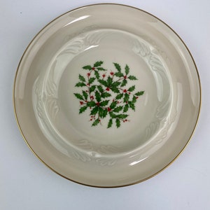 Könnte beinhalten: Eine weiße Keramikschale mit goldfarbenem Rand und einem Weihnachtssterndesign. Die Schale hat einen erhöhten Rand und einen gewellten Rand.