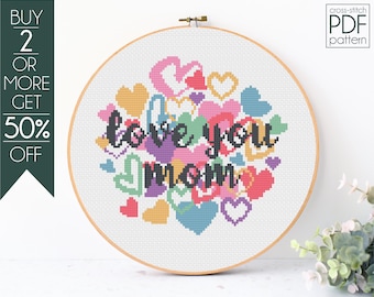Puede incluir: Patrón de punto de cruz PDF para un diseño que dice "love you mom" rodeado de corazones coloridos.