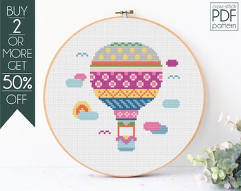 May include: Cross-stitch pattern PDF for a colorful hot air balloon with clouds and a sun. The pattern is in a hoop and the text "cross-stitch PDF pattern" is in the top right corner.