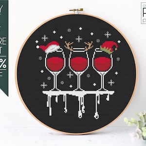 May include: Cross-stitch pattern featuring three wine glasses with Christmas hats and reindeer antlers on a black background. The glasses are filled with red wine and are dripping with a white liquid. The text "cross-stitch PDF pattern" is in the upper right corner.