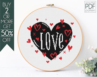 May include: Cross-stitch pattern featuring a black heart with the word "Love" in white lettering. The heart is surrounded by small red hearts.