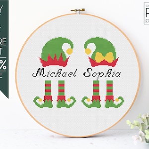 May include: Cross-stitch pattern featuring two elves with the names "Michael" and "Sophia" embroidered below. The elves are wearing green hats, red and green striped stockings, and green shoes with yellow buckles.