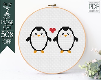 May include: Cross-stitch PDF pattern featuring two pixelated penguins holding hands with a red heart between them. The design is framed in a wooden embroidery hoop. Text on the left says "BUY 2 OR MORE GET 50% OFF". The text "cross-stitch PDF pattern" is in the upper right.