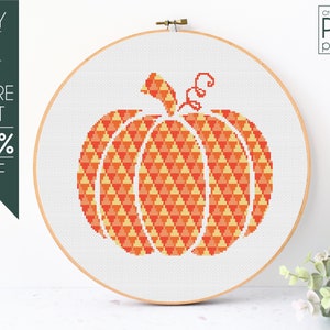 Könnte beinhalten: Kreuzstichmuster für einen Kürbis mit einem geometrischen Design in Orange- und Gelbtönen. Das Muster wird in einem hölzernen Stickrahmen angezeigt.