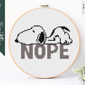 May include: A cross-stitch pattern in a wooden hoop features Snoopy lying on the word "NOPE." The design is in black, white, and gray. The text "BUY 2 OR MORE GET 50% OFF" is on the left, and "cross-stitch PDF pattern" is on the right.