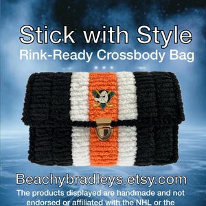 May include: A black, white, and orange crossbody bag with a gold clasp. The bag features the text "Stick with Style" and "Rink-Ready Crossbody Bag". The Anaheim Ducks logo is on the front. The Etsy shop name is displayed.